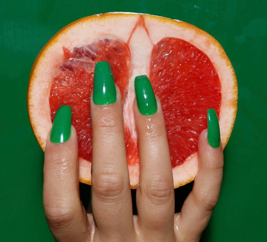 Biodegradable, Sustainable Eco Friendly Press on Green Nails holding a grapefruit 